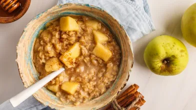 Warm apple cinnamon oatmeal in a bowl with a spoon.