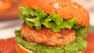 Turkey burger on whole grain bun with sauce and lettuce.