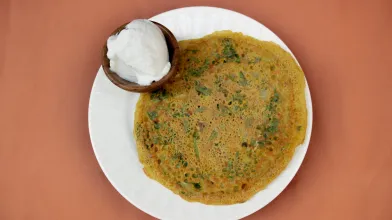 Savory pancake on a white plate with a side of yogurt.