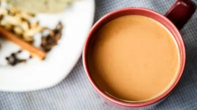 Chai tea in a red mug next to a plate of dried spices.