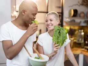 A couple joking together while making a salad for a healthy diet