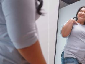 Smiling young Asian woman looking at herself in the mirror