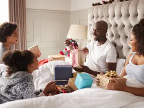 Family Opening Presents In Bed On Christmas Morning