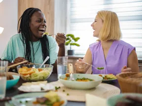 Smiling women at table eating healthy food