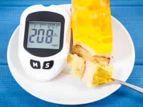 Glucose meter showing 208 mg/dL beside a slice of cake with a fork.