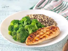 Grilled chicken, broccoli, and quinoa on a white plate.