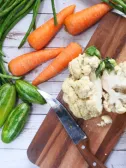A chopping board with cauliflower surrounded by veggies perfect for a healthy diabetic diet