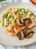 Salmon with mushrooms and potato mash and vegetables on plate.