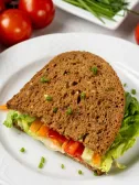 Sandwich on wheat bread with lettuce, colorful bell peppers, hummus