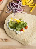 Healthy wrap with creamy spread, cucumbers, tomatoes, yellow peppers, and fresh dill.