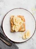 Peanut butter and banana toast on a white plate.