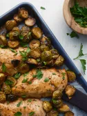Roasted chicken breasts and Brussels sprouts on a sheet pan.