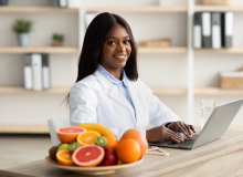 African American research at laptop computer next to plate with fruit