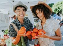 Young couple at farmers market holding tomatoes