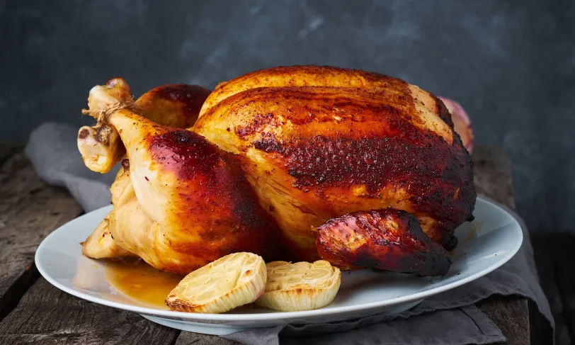 Whole roasted chicken on a plate with onions