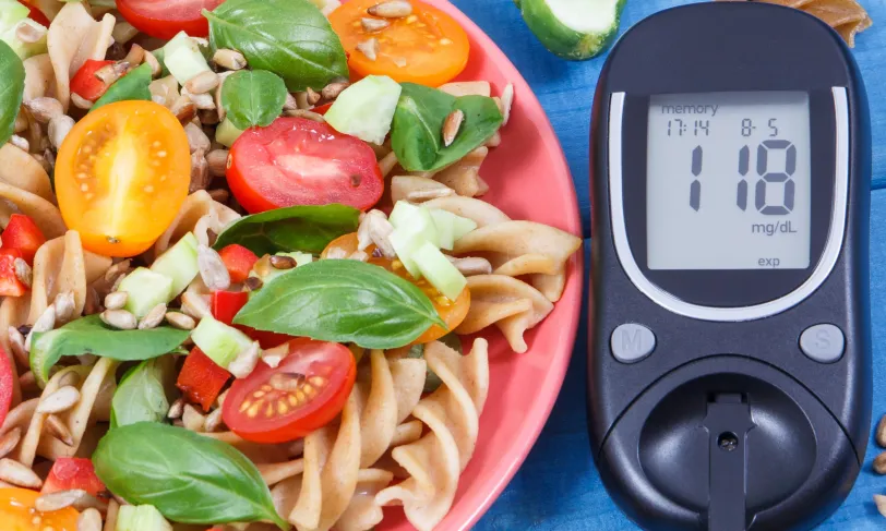 healthy pasta salad next to blood glucose level on blood glucose meter