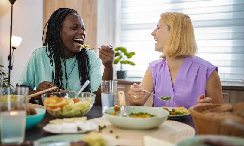 Smiling women at table eating healthy food