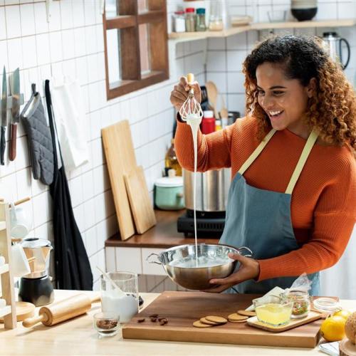 Smiling African American woman making food in kitchen