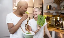 A couple joking together while making a salad for a healthy diet