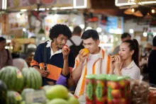 A group of friends at a market inspecting produce and enjoying the smells as a means of mindful eating for healthier life choices around diabetes management