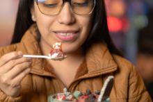 A woman eating a spoon of strawberry and cream for a fruit forward dessert