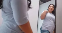Smiling young Asian woman looking at herself in the mirror
