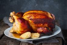 Whole roasted chicken on a plate with onions