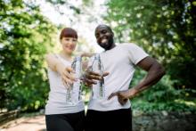 Smiling couple out for a jog in park holding water bottles