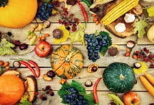 Various fall fruits and vegetables on a wooden surface.