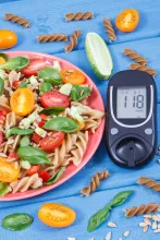 healthy pasta salad next to blood glucose level on blood glucose meter