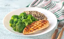 Grilled chicken, broccoli, and quinoa on a white plate.