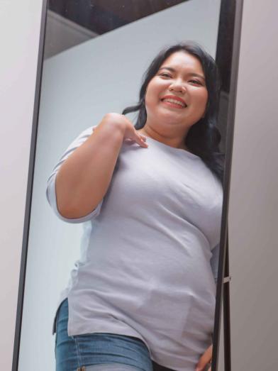 Smiling young Asian woman looking at herself in the mirror