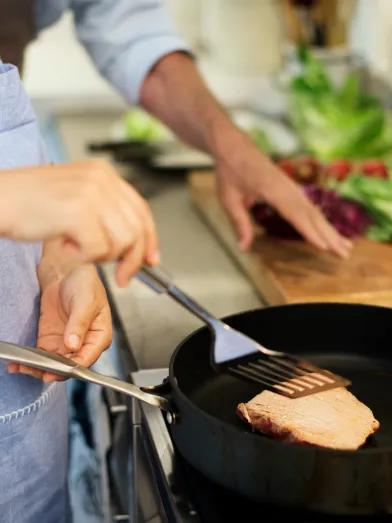 woman frying up lean meat in skillet