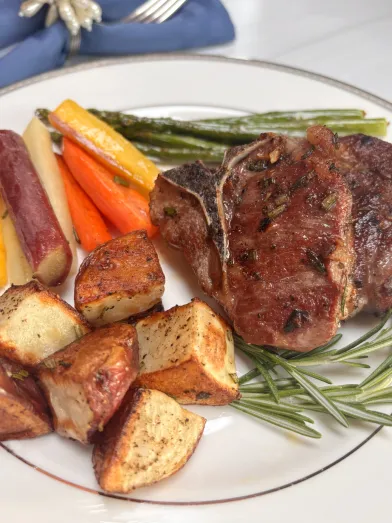 A plate with lamb chops, potatoes, and spring vegetables.