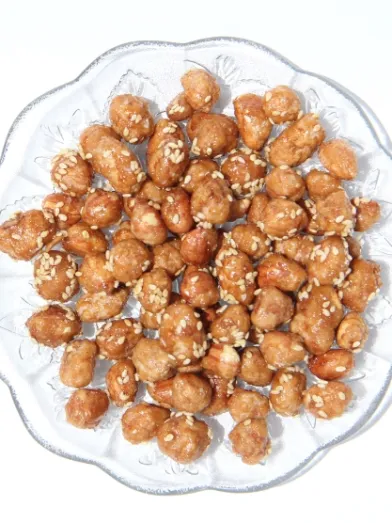 Spiced peanuts with sesame seeds on a clear glass plate.