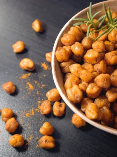 Roasted chickpeas in a bowl on a dark table.