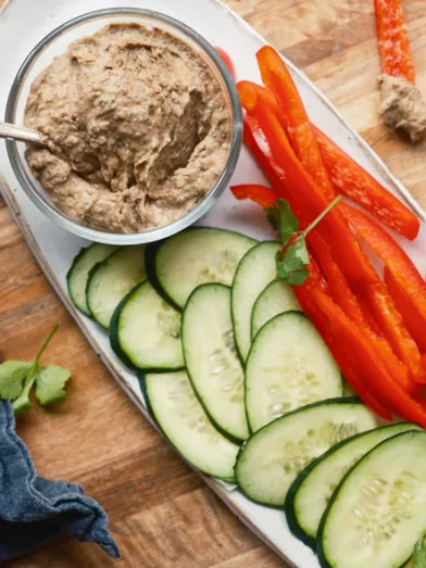 Snack platter with black bean dip, sliced cucumbers, and red bell peppers.
