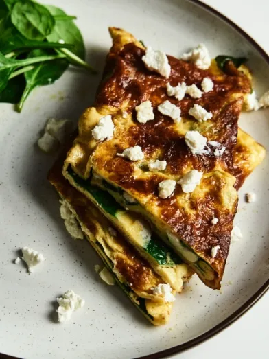 Spinach and feta omelet with fresh spinach on a white plate.