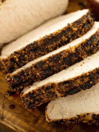 Sliced, seasoned pork loin on a cutting board