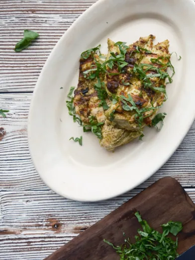 Healthy grilled chicken breasts with fresh herbs on a plate.