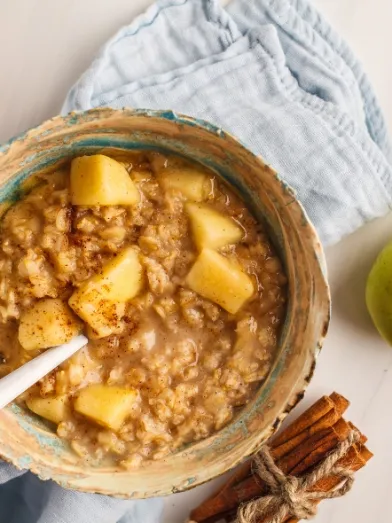 Warm apple cinnamon oatmeal in a bowl with a spoon.