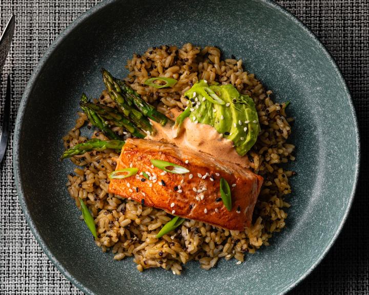 air fryer salmon with yum yum sauce on bed of rice, asparagus, and avocaco slices