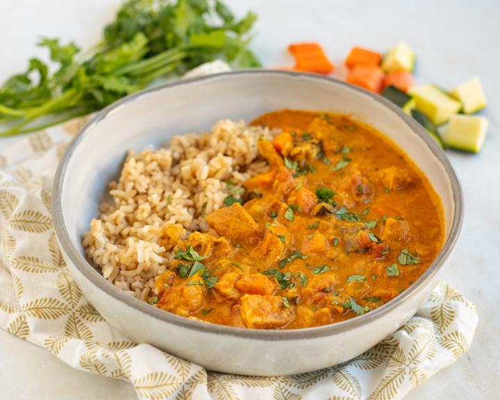 A bowl of richly spiced Indian butter chicken served with brown rice for a health Indian diet