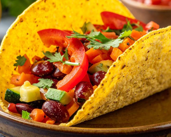 A corn tortilla taco filled with vegetables on a plate. 
