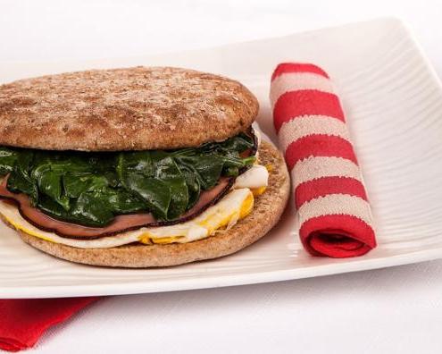 sandwich with spinach and folded striped towel on a plate