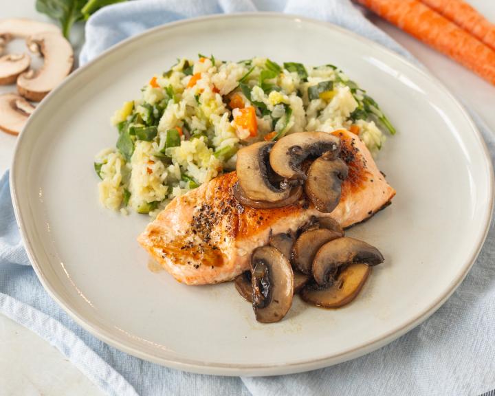 Salmon with mushrooms and potato mash and vegetables on plate.