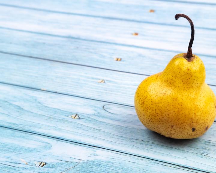Single yellow pear on blue table