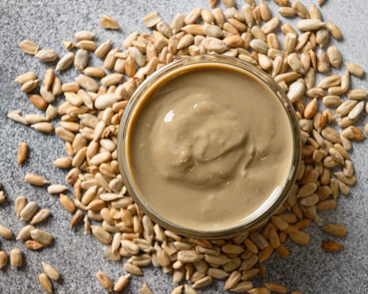 Sunflower seed butter in jar surrounded by sunflower seeds