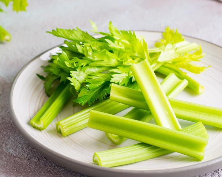 Fresh chopped celery stalks and leaves on a white plate.