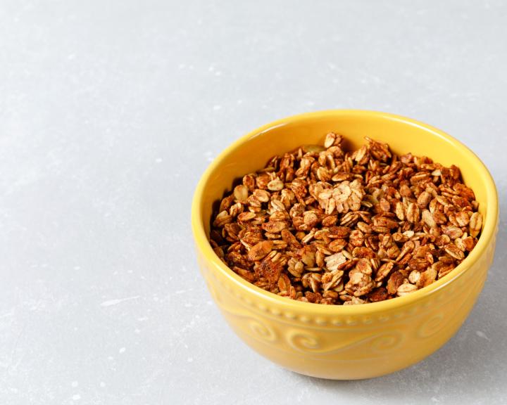 Yellow bowl filled with gluten-free granola on a light gray surface.